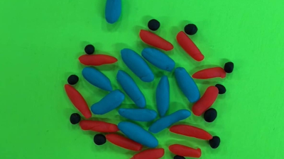 a bunch of long, cylindrical blue pieces of clay surrounded by similar red pieces of clay and smaller black balls of clay