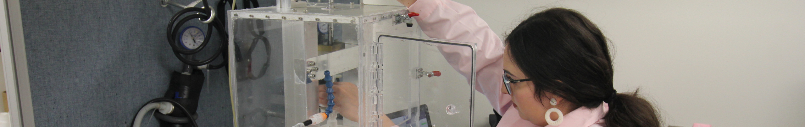 A Duke CEE student reaches into equipment in a laboratory