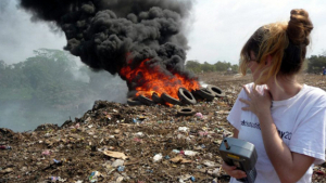Heidi Vreeland stands in front of a trash fire