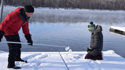 Scientists take a water sample from a river in winter