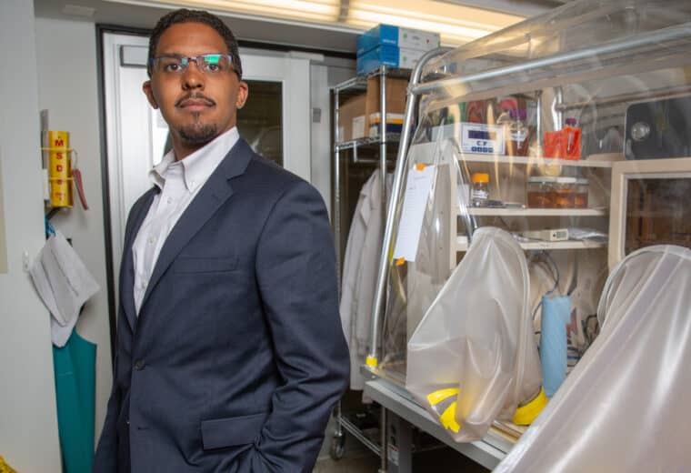 A man in a suit and glasses standing in a laboratory