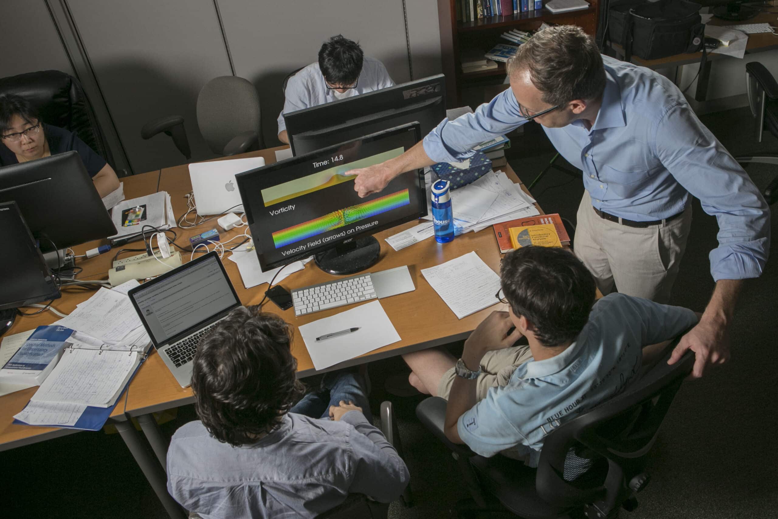 Guglielmo Scovazzi at a computer with colleagues and students who work in his lab