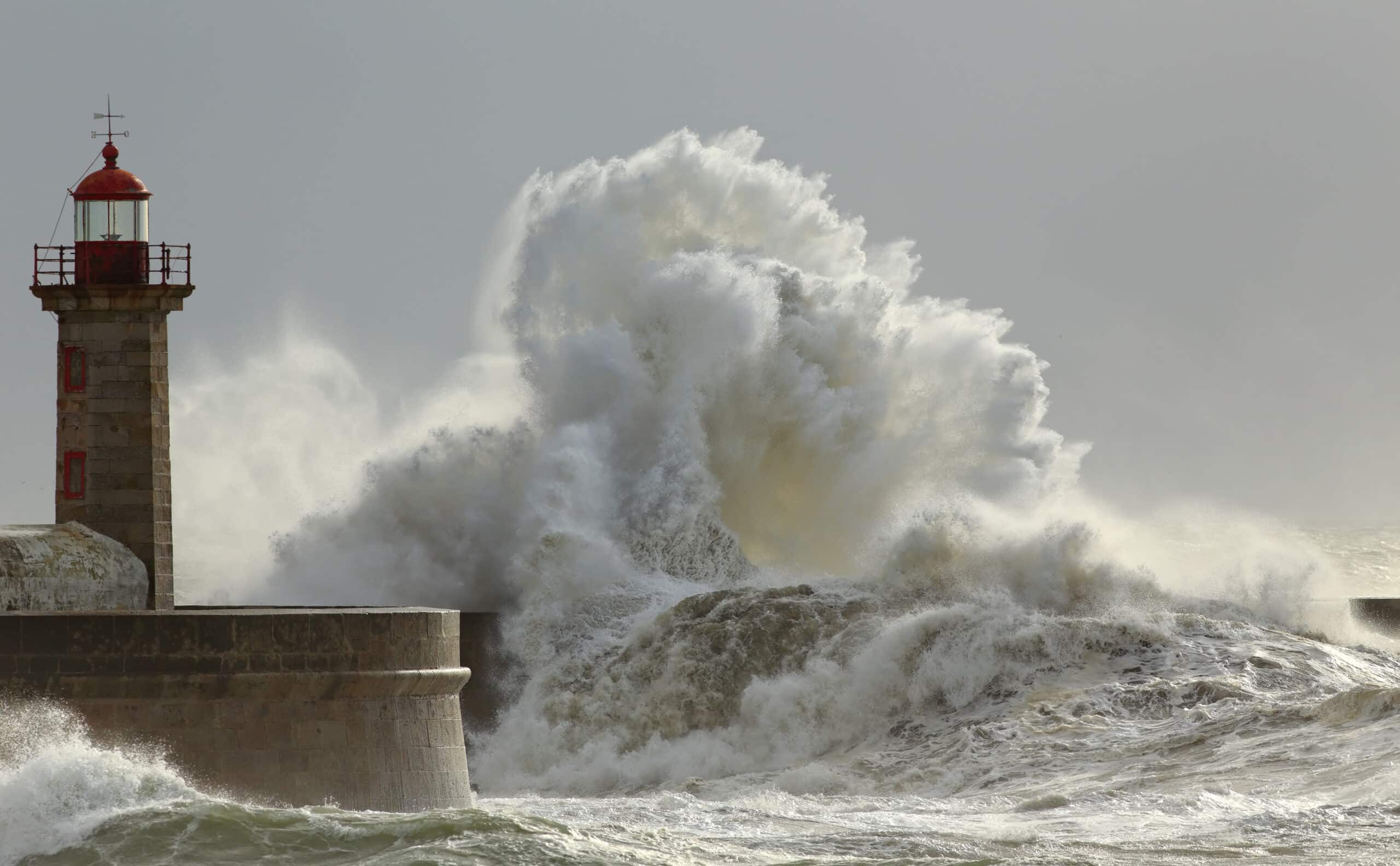 waves crash against a lighthouse